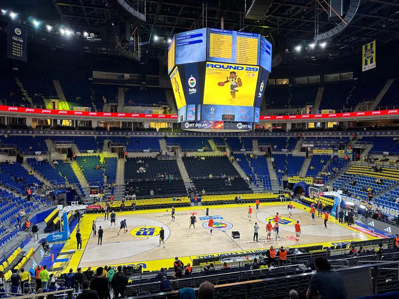 Players warming up on a yellow and navy court before a European league game